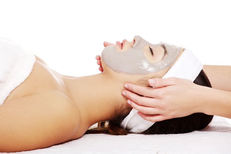 Beauty treatment in spa salon. Woman with facial clay mask.