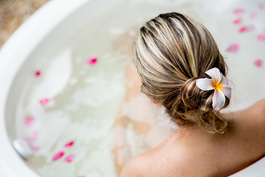 Back of woman in a bathtub and a flower in her hair